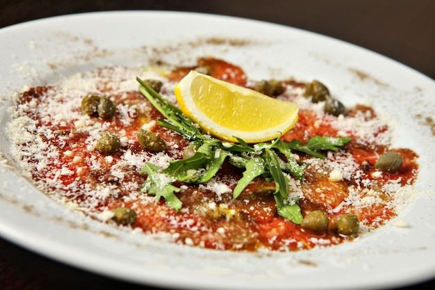 Carpaccio on plate with rucola and lemon