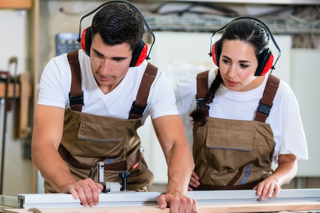 Carpenter and apprentice working together in wood workshop