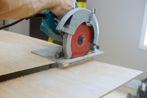 Carpenter cuts plywood on a electric circular saw