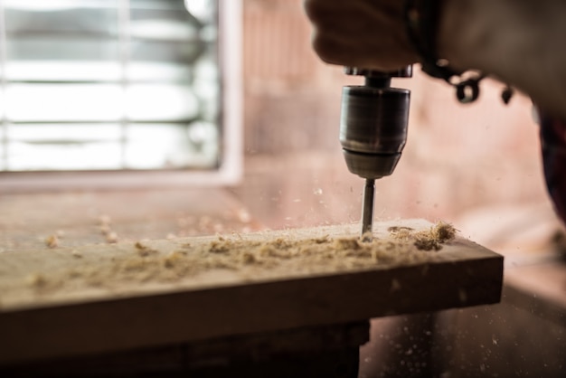 Carpenter drills a hole with an electric drill