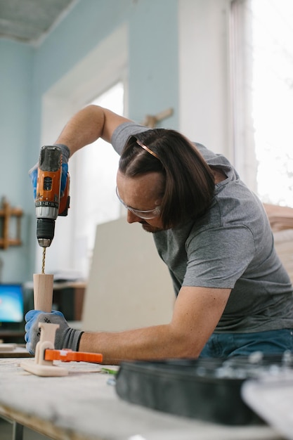 Carpenter drills a hole with an electrical drill