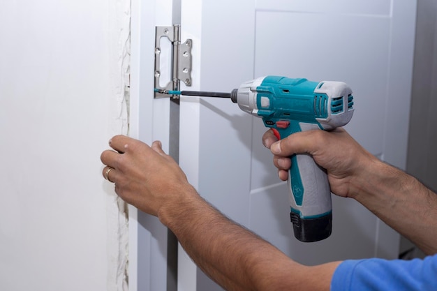 A carpenter drills a hole in a wooden board with an electric drill