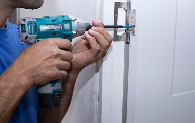 A carpenter drills a hole in a wooden board with an electric drill