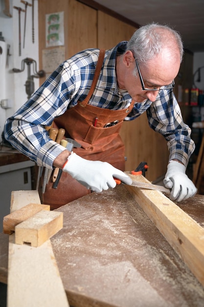 Carpenter filing a plank of wood in his Workshop