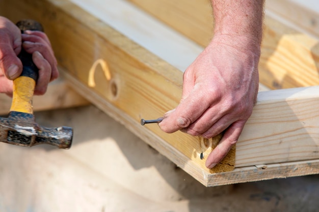 Carpenter hammering nail into the wood by hammer Joiner with hammer and nail closeup