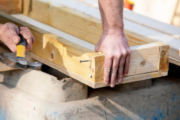 Carpenter hammering nail into the wood by hammer Joiner with hammer and nail closeup