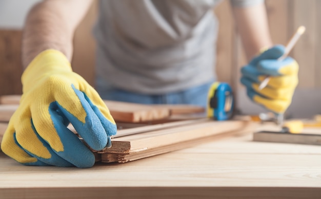 Carpenter making marks on wooden plank with a pencil.