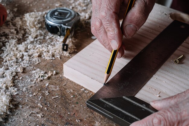 Photo carpenter making measurements on a table with a pencil and a metal square