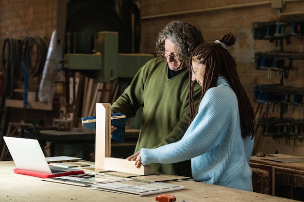 Carpenter making wooden frame while talking to client