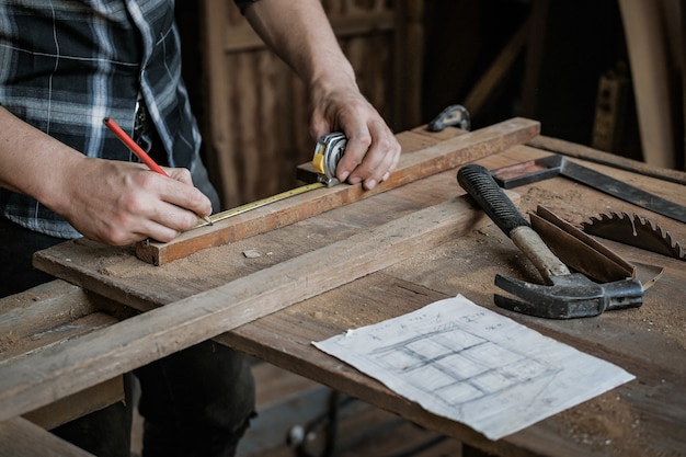 Carpenter men work on the measurements of wood in a carpentry shop.