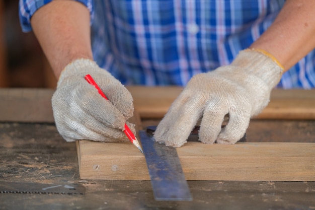 Carpenter men work on the measurements of wood in a carpentry shop.