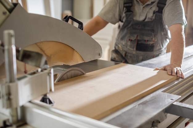 Carpenter processes wooden beam on plane machine