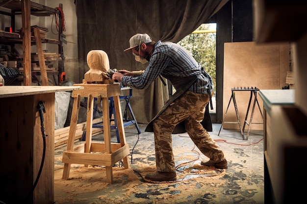 Carpenter  saw to cut out sculpture from wooden a man's head