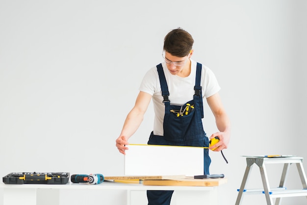 Carpenter sawing white board during apartment renovating