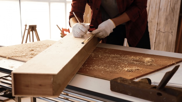 Carpenter using tape measure to scale size of board.