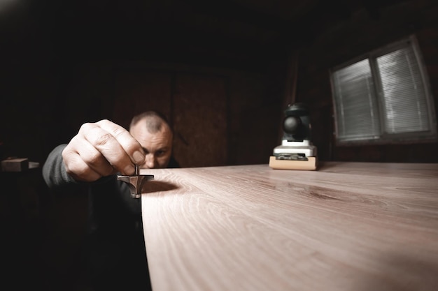 Carpenter with hand electric router machine at work Trying on a cutter