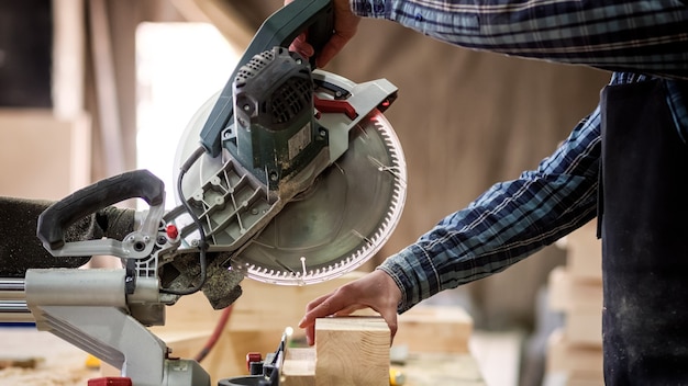 Photo carpenter in work clothes  doing woodwork in carpentry. small buiness owner cut on wood plank