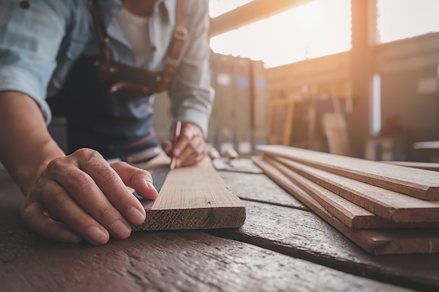 Carpenter working with equipment on wooden table in carpentry shop. 