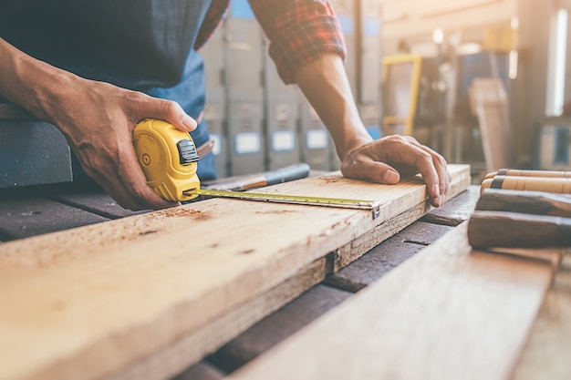 Carpenter working with equipment on wooden table in carpentry shop. 