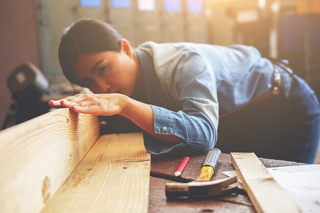 Carpenter working on woodworking machines in carpentry shop.