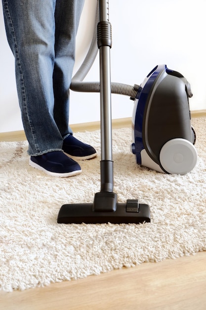 Carpet cleaning with a vacuum cleaner in the house Cleaner legs close up