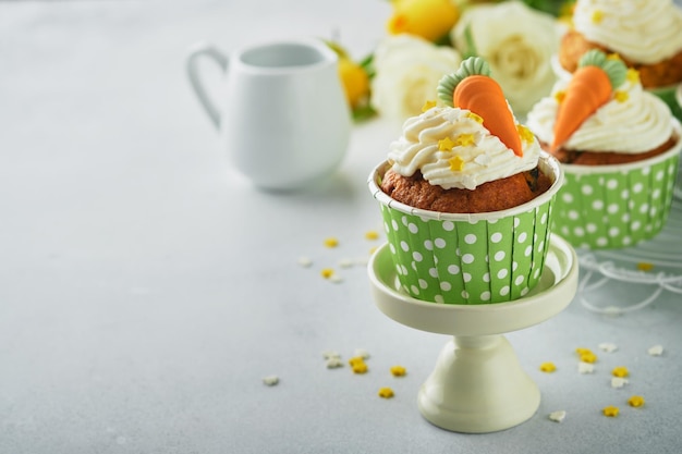 Carrot cake cupcakes for Easter Carrot cupcakes with cream cheese frosting decorated with tiny marzipan carrots on white background Happy Easter and spring holiday concept Holydays homemade dessert