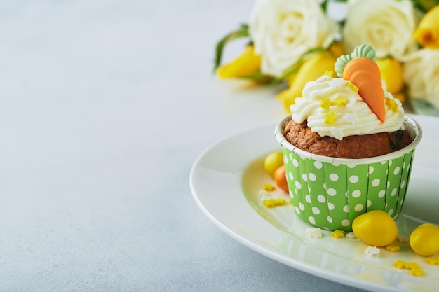 Carrot cake cupcakes for Easter Carrot cupcakes with cream cheese frosting decorated with tiny marzipan carrots on white background Happy Easter and spring holiday concept Holydays homemade dessert