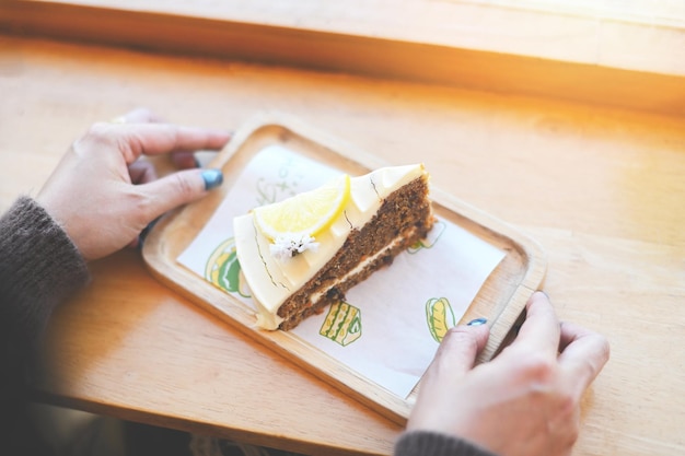 Carrot cake on wooden plate woman served carrot cake with lemon for dessert and tea fresh homemade carrot cake cake slice