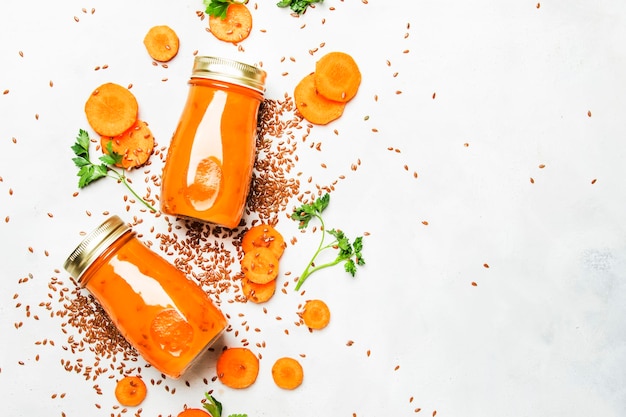 Carrot smoothies with flax seeds in glass bottles vegan beverage healthy drink for clean raw diet white background top view