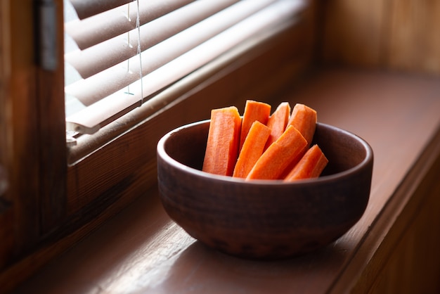 Carrots in plate on a wooden background. Healthy raw food diet, vegetarian, natural vitamins.