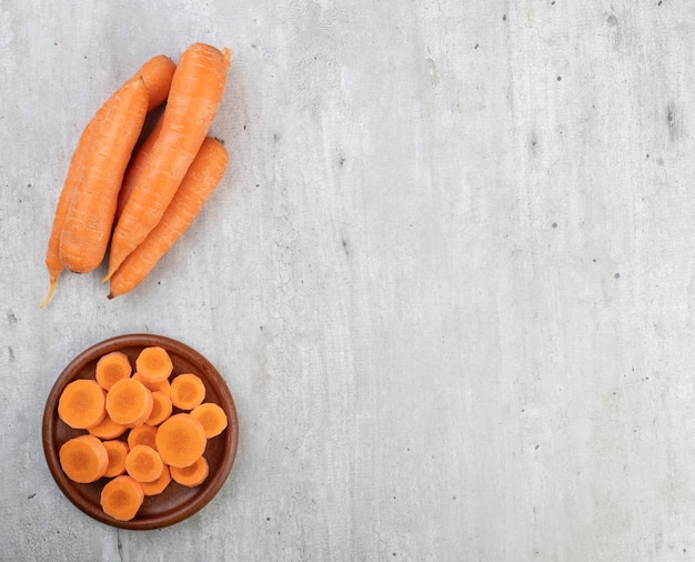 Carrots and slices on a plate over wooden table with copy space.