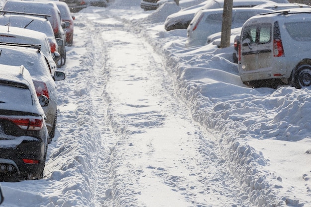 Cars buried under snow in parking near residental building at sunny day light