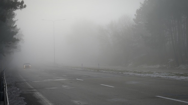 Cars in the fog Bad winter weather and dangerous automobile traffic on the road Light vehicles in fog