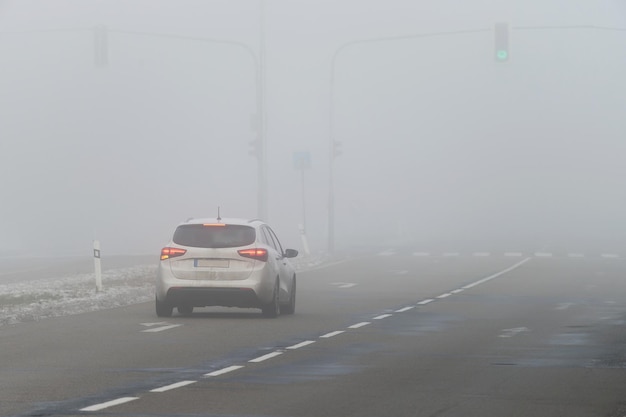 Cars in the fog Bad winter weather and dangerous automobile traffic on the road Light vehicles in fog