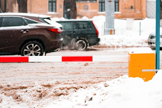 Cars move through a snowy city near a parking red and white barrier Dirty Snow City Winter Street Outdoor Transportation Blizzard Heap Climate Weather White Road