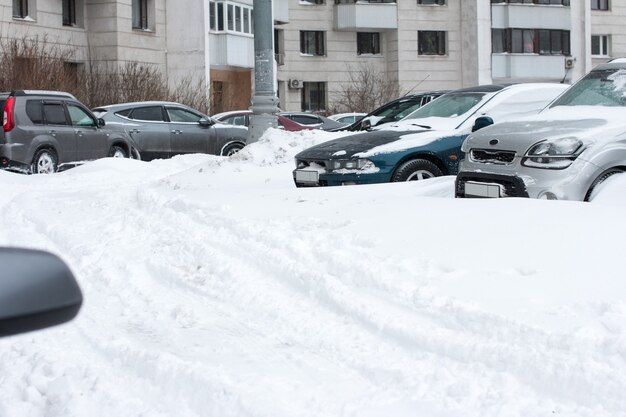 Photo cars parked in the yard in winter. vehicles covered with snow during heavy snowfall.