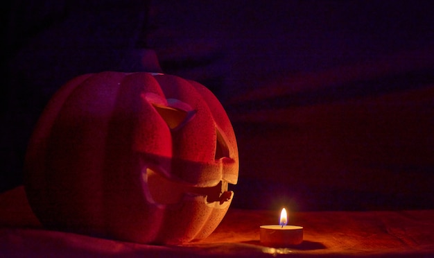 Photo a carved pumpkin and a candle in a dark background - halloween concept