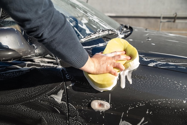 Carwash concept man wash car with soap and yellow sponge