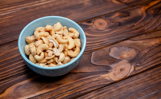 Cashew nuts in bowl on wooden background. Roasted salted cashews