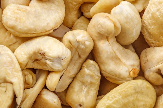 Cashew nuts lot of peeled fried piled in pile closeup