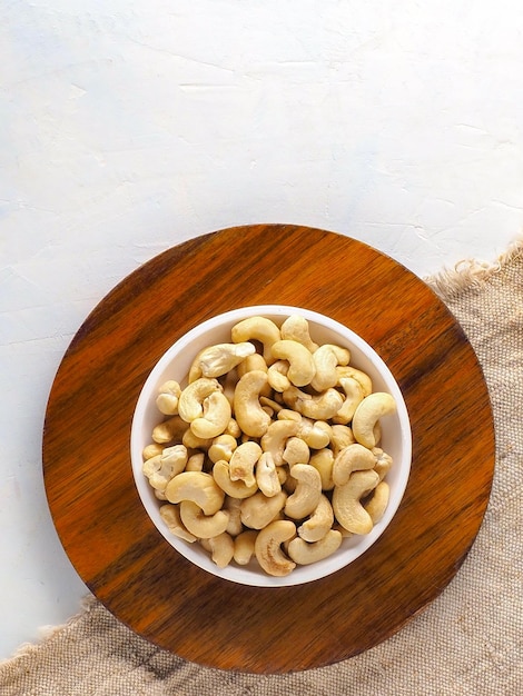 Cashew nuts in plate on wooden stand top view with copy space Preparation for online store or marketplace Vertical photo