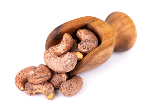 Cashew nuts in shell in wooden scoop isolated on white background Roasted and salted cashew nuts