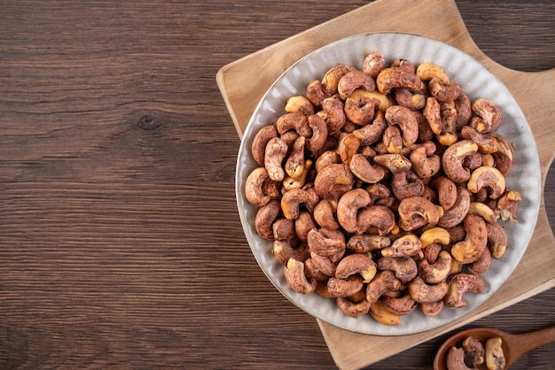 Cashew nuts with peel in a plate on wooden tray and table background healthy raw food plate