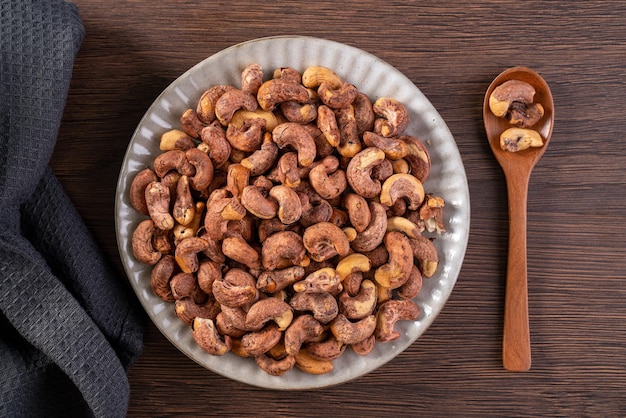 Cashew nuts with peel in a plate on wooden tray and table background healthy raw food plate