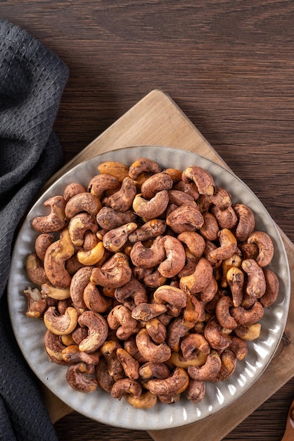 Cashew nuts with peel in a plate on wooden tray and table background healthy raw food plate