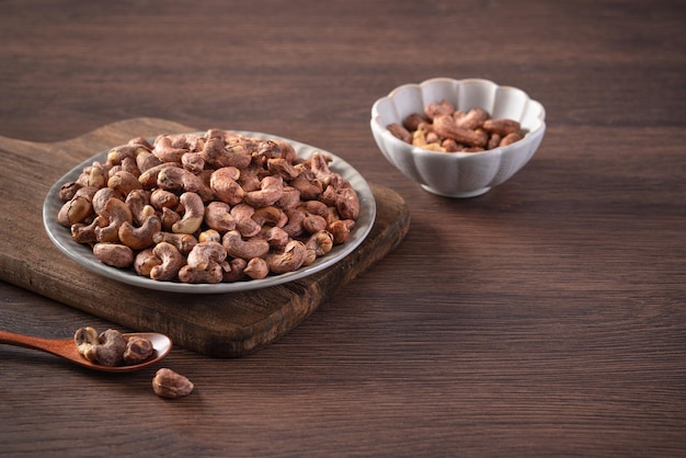 Cashew nuts with peel in a plate on wooden tray