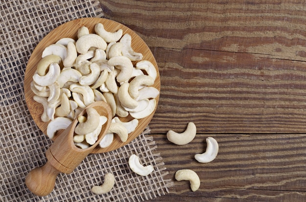 Cashew nuts with scoop on the wooden table, top view with copy space