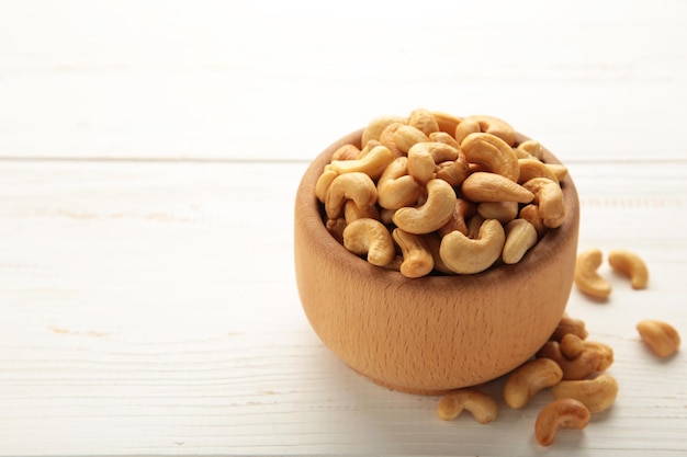 Cashew nuts on wooden bowl on white background. Vertical photo.