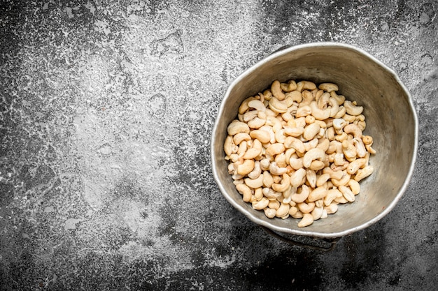 Cashews in the old bucket. On rustic background.