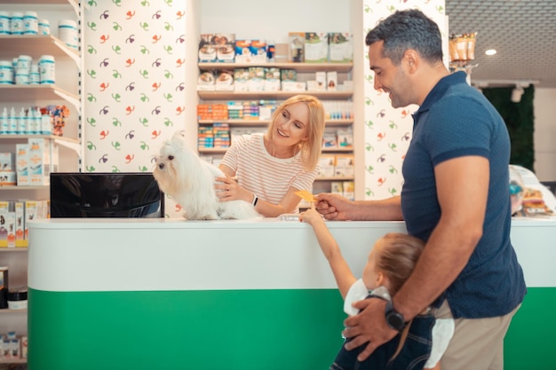 Cashier selling cute white fluffy dog for man with daughter